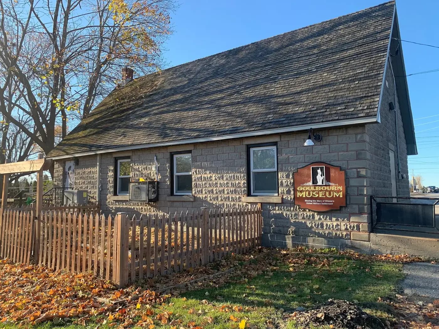 Stone Goulbourn Museum building with a picket fence in autumn